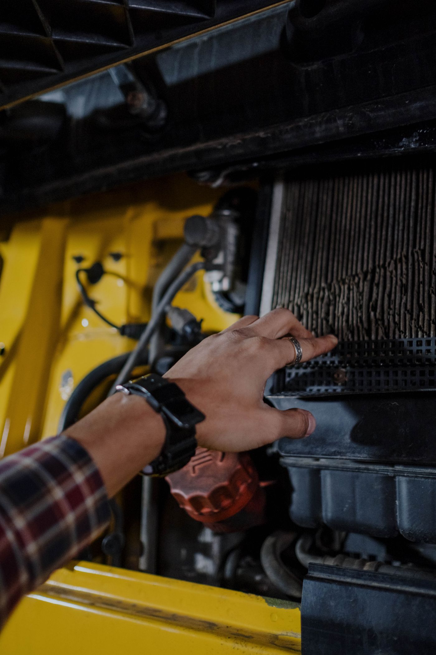 Hand inspecting a filter inside a yellow vehicle.