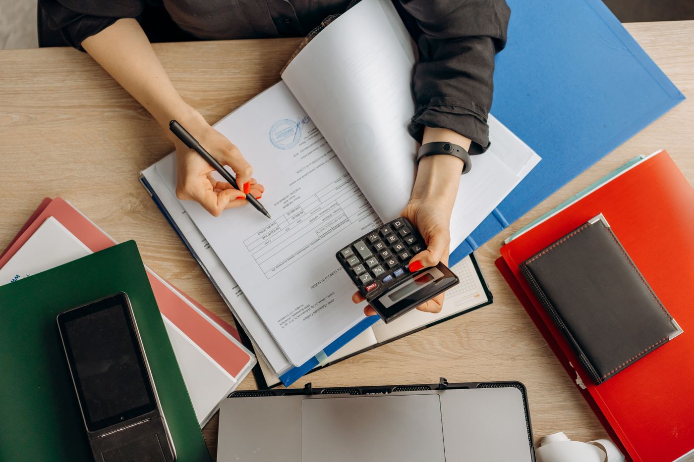 Hands reviewing paperwork with a calculator.